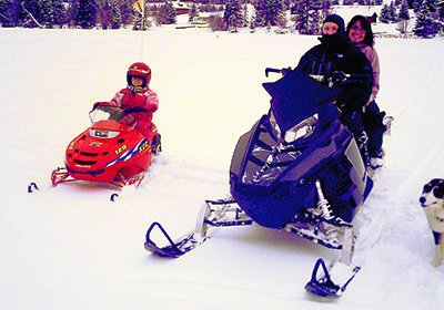 Vacationing from Edmonton, Cody and Lindsay Stewart sledded around Lac des Roches accompanied by their young daughter, Emily, who was riding her first mini snowmobile. — image credit: Sharron Woloshyn